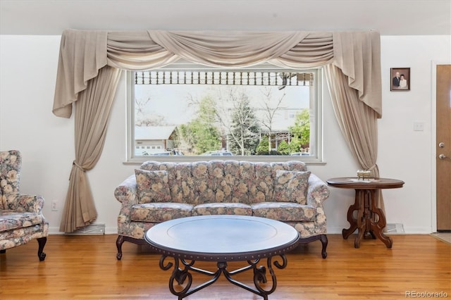 living area with visible vents, wood finished floors, and baseboards