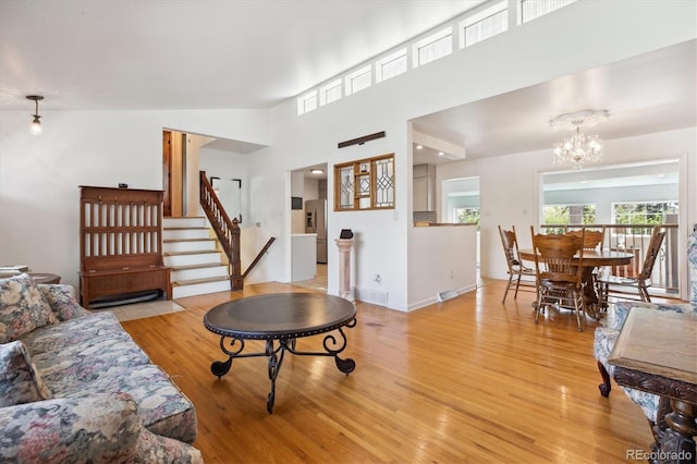 living area featuring an inviting chandelier, stairs, visible vents, and light wood-style floors