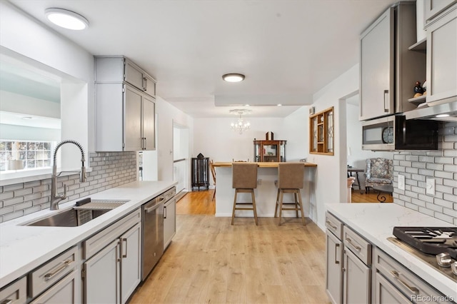 kitchen featuring a sink, an inviting chandelier, stainless steel appliances, and decorative backsplash