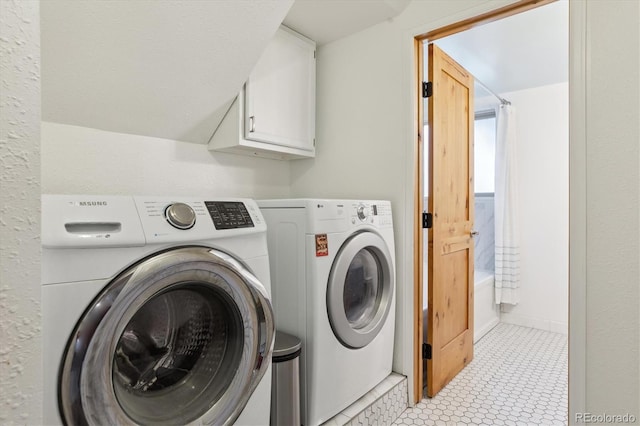 clothes washing area featuring washer and dryer and cabinet space