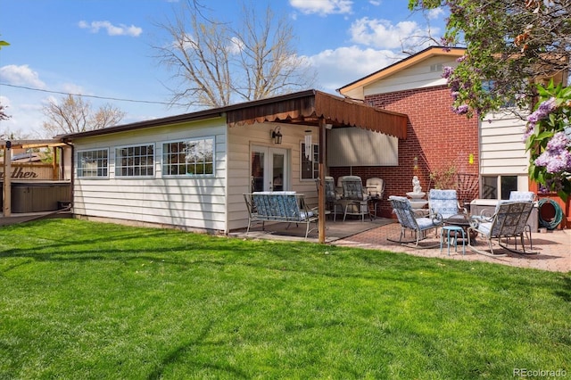 rear view of house with a lawn, a patio, french doors, and brick siding