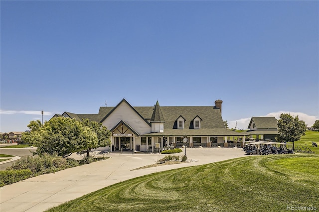 rear view of house with covered porch, a chimney, and a yard