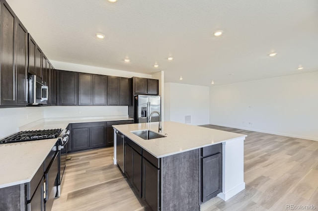 kitchen with a sink, light wood-style flooring, dark brown cabinets, and stainless steel appliances