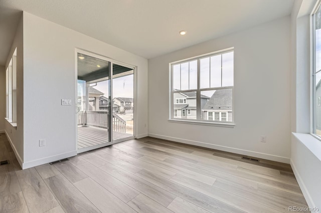spare room with baseboards, visible vents, and wood finished floors