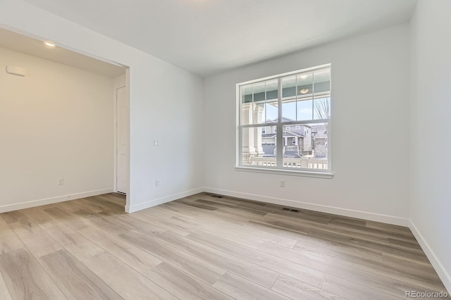 unfurnished room featuring baseboards, light wood finished floors, and visible vents