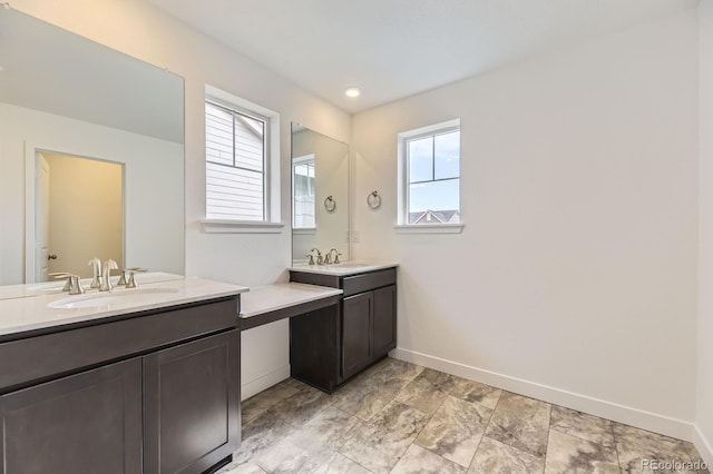 bathroom with baseboards, a sink, and two vanities
