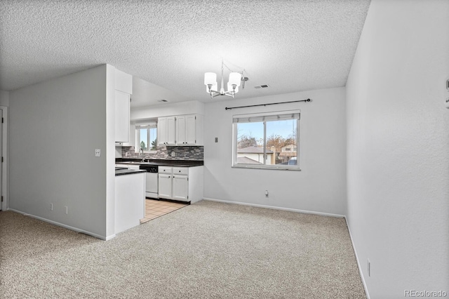 kitchen with backsplash, white dishwasher, light colored carpet, white cabinetry, and a chandelier