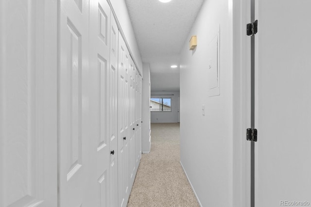 corridor with light colored carpet and a textured ceiling