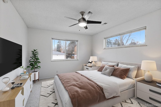 carpeted bedroom with ceiling fan and a textured ceiling