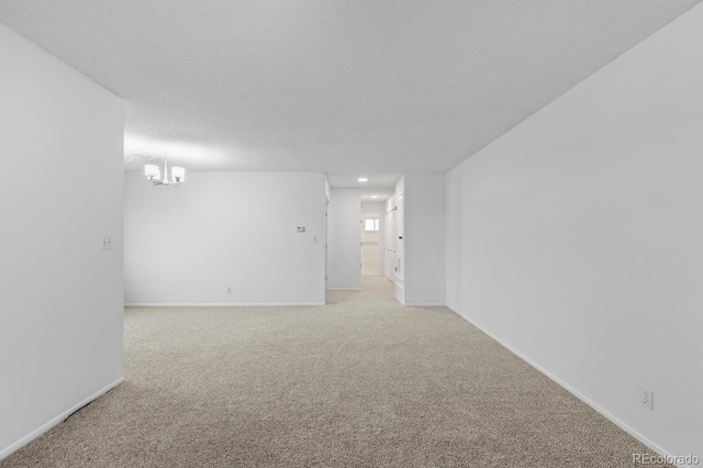 empty room with carpet floors, a chandelier, and a textured ceiling