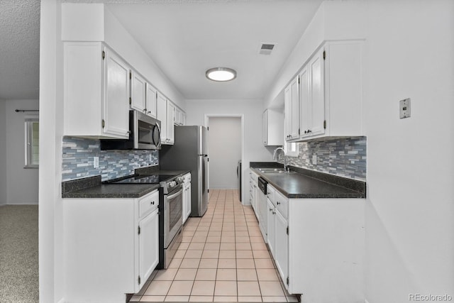 kitchen featuring tasteful backsplash, stainless steel appliances, sink, light tile patterned floors, and white cabinets