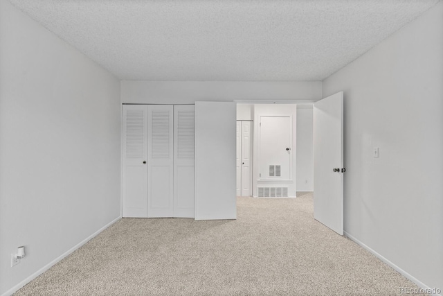 unfurnished bedroom with a textured ceiling, carpet floors, and a closet