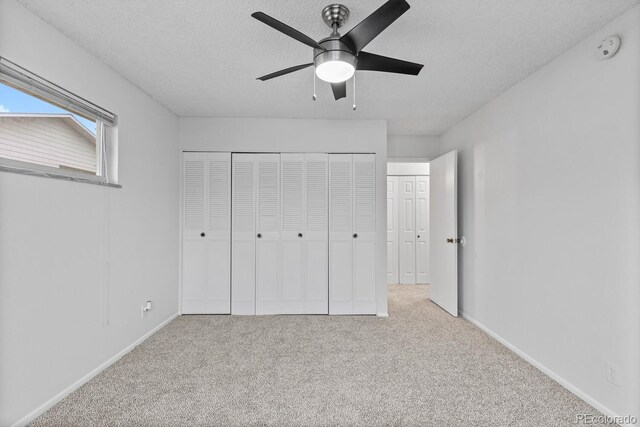 unfurnished bedroom with ceiling fan, light colored carpet, and a textured ceiling