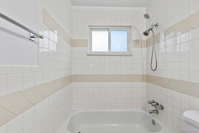 bathroom with tiled shower / bath combo and toilet