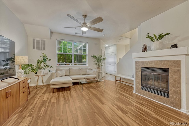 7140 Simms St Unit 102, Arvada, CO 80004 - living area with light wood-style floors, a tile fireplace, ceiling fan, and baseboards