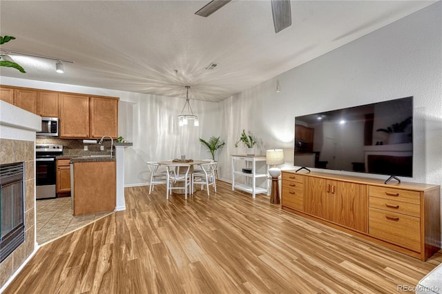 7140 Simms St Unit 102, Arvada, CO 80004 - kitchen with stainless steel appliances, tasteful backsplash, light wood finished floors, a ceiling fan, and brown cabinets