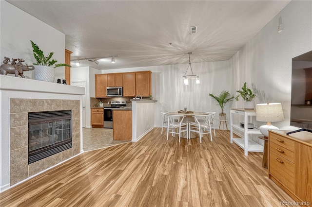7140 Simms St Unit 102, Arvada, CO 80004 - kitchen featuring appliances with stainless steel finishes, light wood-style flooring, decorative backsplash, and brown cabinets