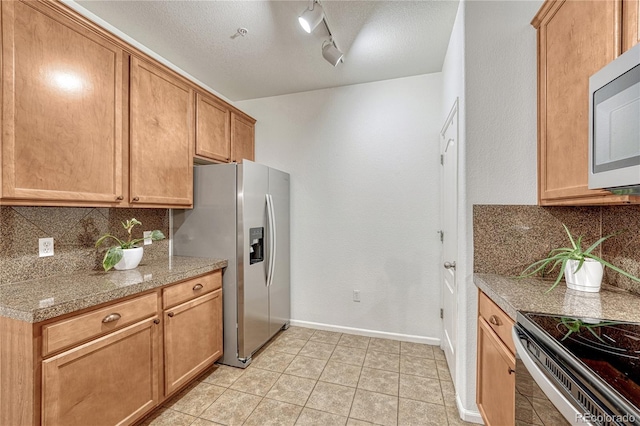 7140 Simms St Unit 102, Arvada, CO 80004 - kitchen with stainless steel appliances, tasteful backsplash, baseboards, light tile patterned flooring, and a textured ceiling