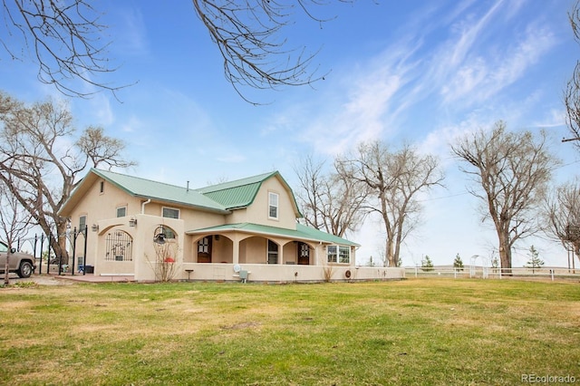 view of front facade with stucco siding, metal roof, a front lawn, and fence