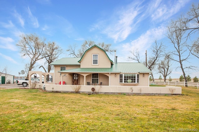 view of front facade with fence, a porch, a front yard, stucco siding, and metal roof