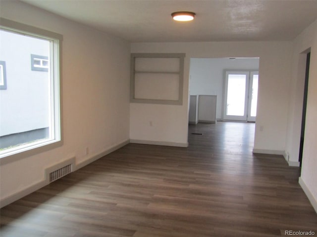 empty room featuring plenty of natural light, dark hardwood / wood-style flooring, and built in shelves