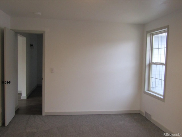 spare room with dark carpet and a healthy amount of sunlight