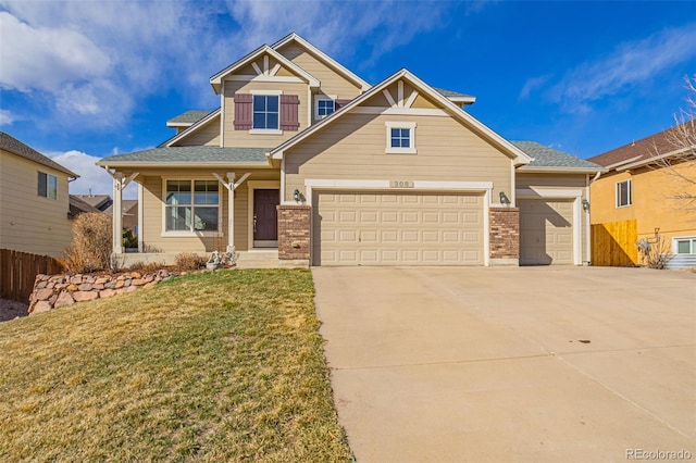 craftsman house featuring a front yard, fence, an attached garage, concrete driveway, and brick siding