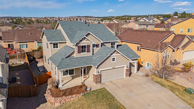 view of front facade with a residential view, roof with shingles, concrete driveway, and fence