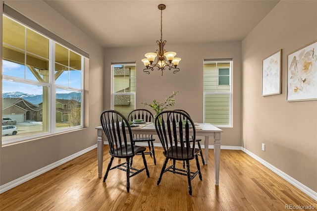 dining area with a mountain view, baseboards, light wood-style floors, and an inviting chandelier