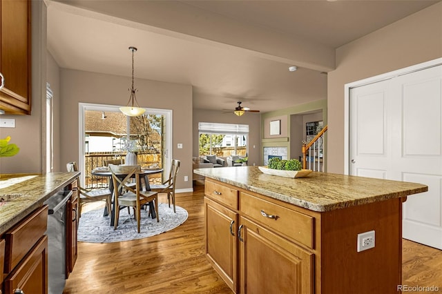 kitchen with a kitchen island, light wood-type flooring, hanging light fixtures, a ceiling fan, and stainless steel dishwasher