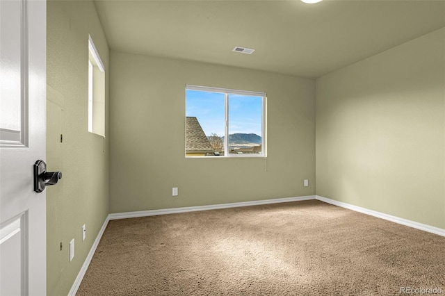 carpeted spare room featuring visible vents and baseboards