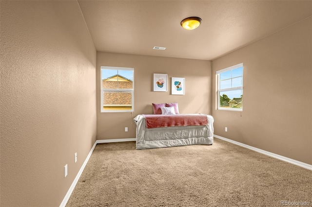 bedroom featuring visible vents, multiple windows, baseboards, and carpet floors