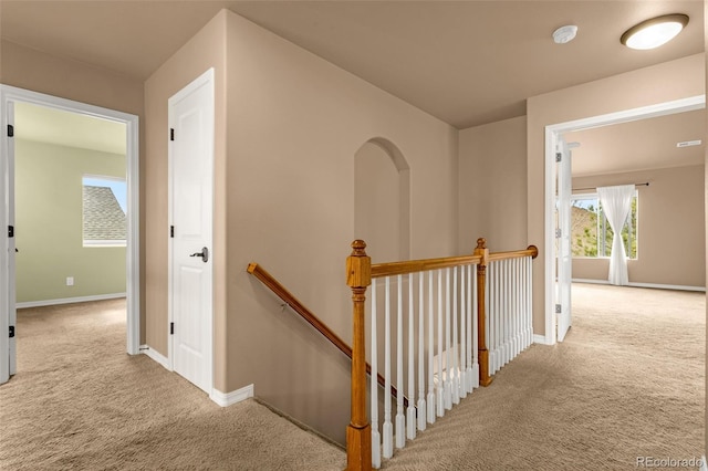 hall with an upstairs landing, baseboards, and carpet