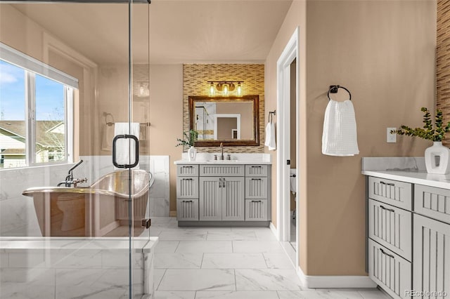 full bathroom featuring baseboards, a freestanding bath, a stall shower, marble finish floor, and vanity