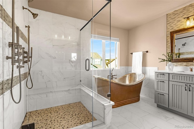 full bathroom featuring vanity, a wainscoted wall, a stall shower, a freestanding bath, and marble finish floor