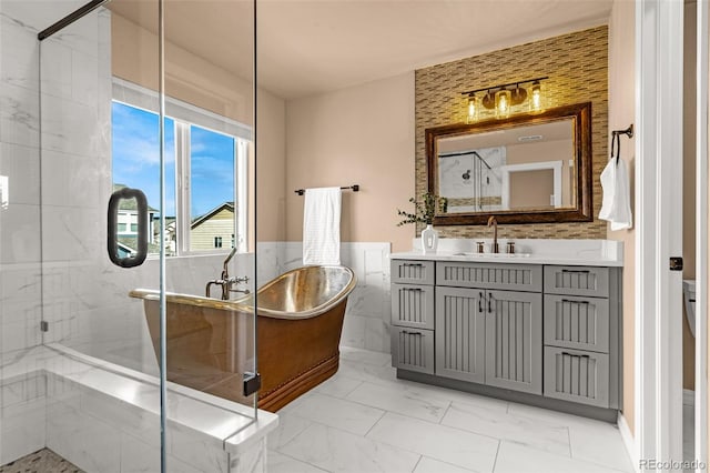 bathroom featuring marble finish floor, a marble finish shower, tile walls, a freestanding bath, and vanity