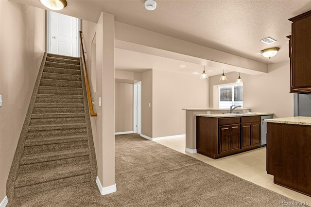 kitchen with visible vents, light carpet, baseboards, dark brown cabinets, and dishwasher