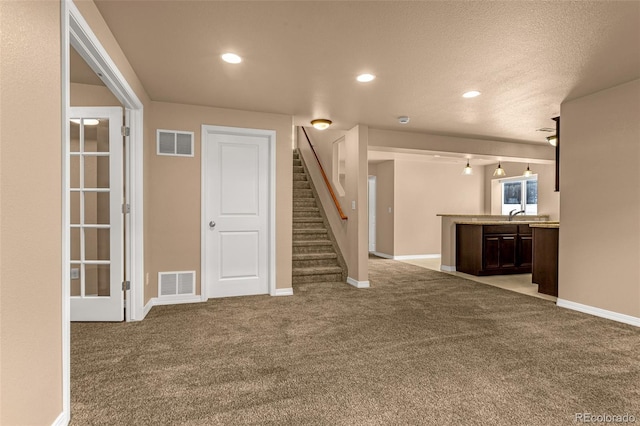 unfurnished living room with stairs, carpet, visible vents, and baseboards