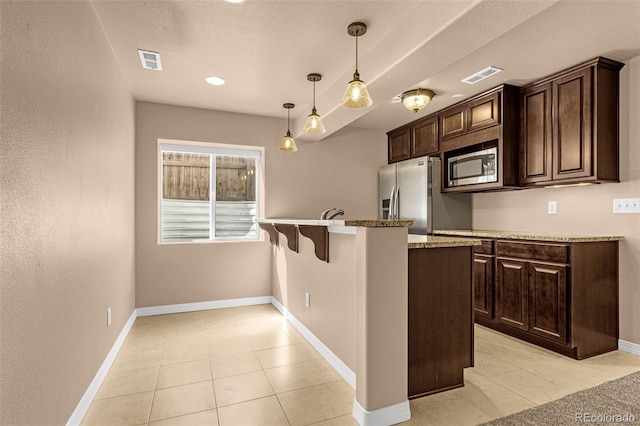 kitchen featuring stainless steel appliances, dark brown cabinetry, visible vents, and a peninsula