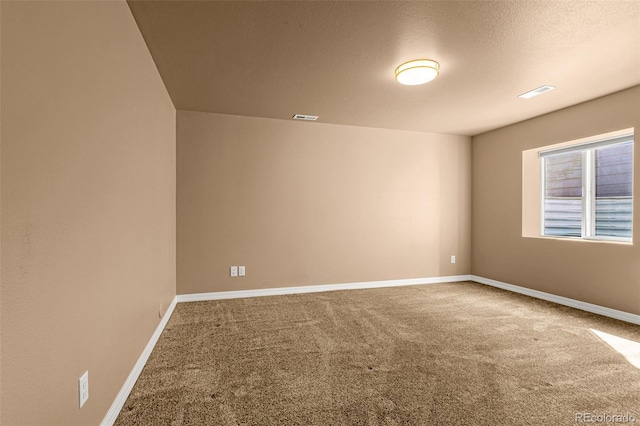 carpeted spare room featuring baseboards, visible vents, and a textured ceiling