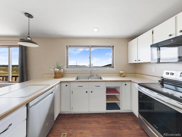 kitchen featuring plenty of natural light, white cabinetry, decorative light fixtures, and stainless steel appliances