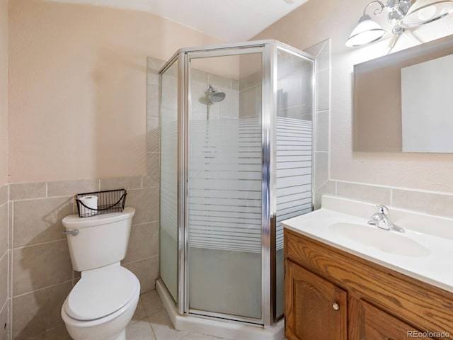 bathroom with a shower with door, vanity, toilet, and tile walls