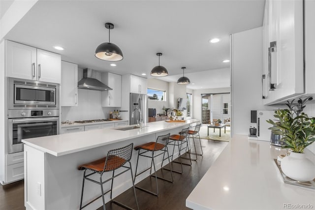 5101 Quitman St, Denver, CO 80212 - kitchen featuring wall chimney exhaust hood, appliances with stainless steel finishes, a sink, dark wood-style floors, and white cabinetry