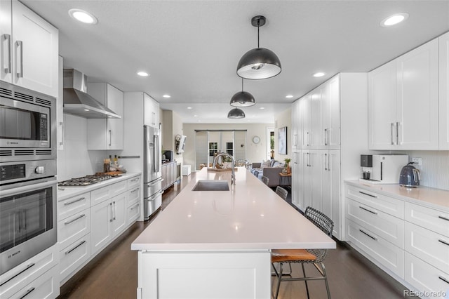 5101 Quitman St, Denver, CO 80212 - kitchen featuring appliances with stainless steel finishes, wall chimney exhaust hood, light countertops, an island with sink, and open floor plan