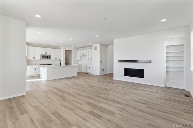 unfurnished living room with light wood-type flooring and sink