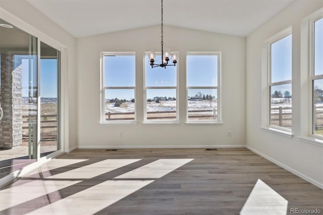 unfurnished dining area featuring a chandelier, lofted ceiling, and dark wood-type flooring