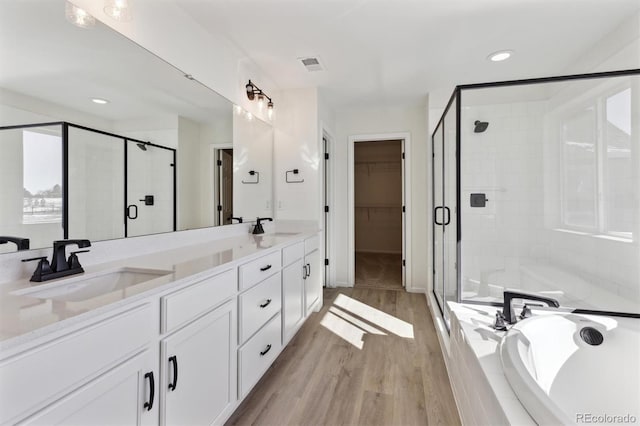 bathroom with vanity, wood-type flooring, and plus walk in shower