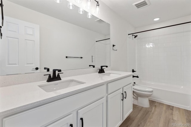 full bathroom featuring toilet, hardwood / wood-style floors, vanity, and tiled shower / bath