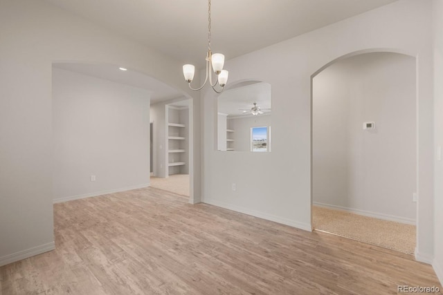 unfurnished room with ceiling fan with notable chandelier, light hardwood / wood-style floors, and built in shelves