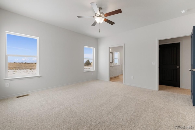 unfurnished bedroom featuring ceiling fan, light colored carpet, and connected bathroom